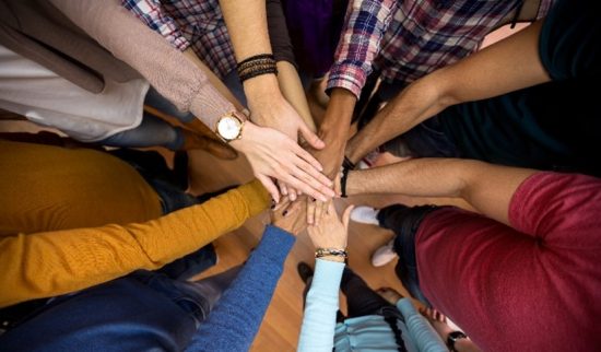 Diverse group of people putting their hands in for a cheer