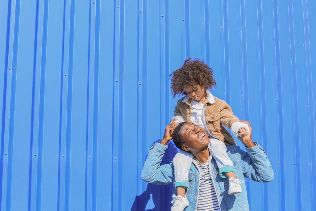 Man looking up at child on his shoulders