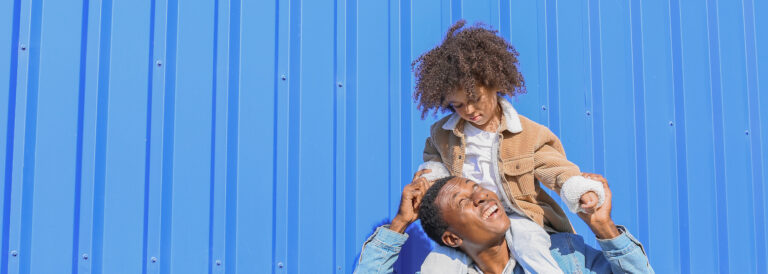 Man looking up at child on his shoulders