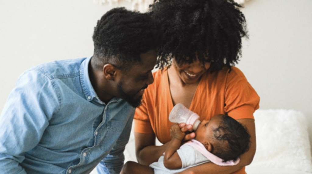 Black mother and father looking at their baby.