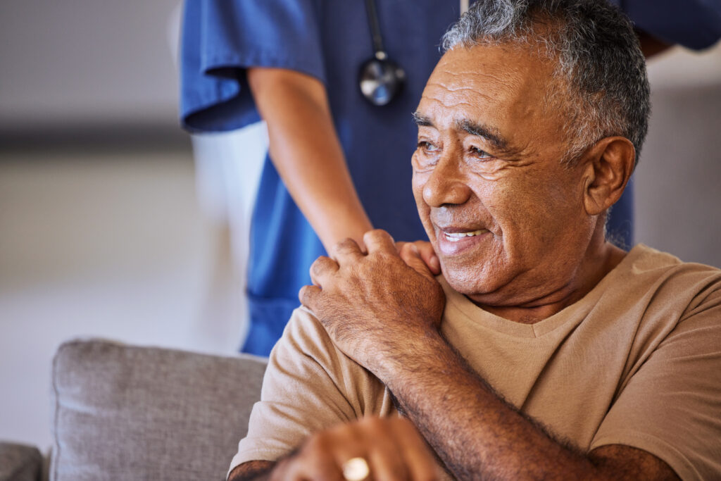 Nurse or doctor offer their man support during recovery or loss. Caregiver holding hand of her sad senior patient and showing kindness while doing a checkup at a retirement, old age home or hospital