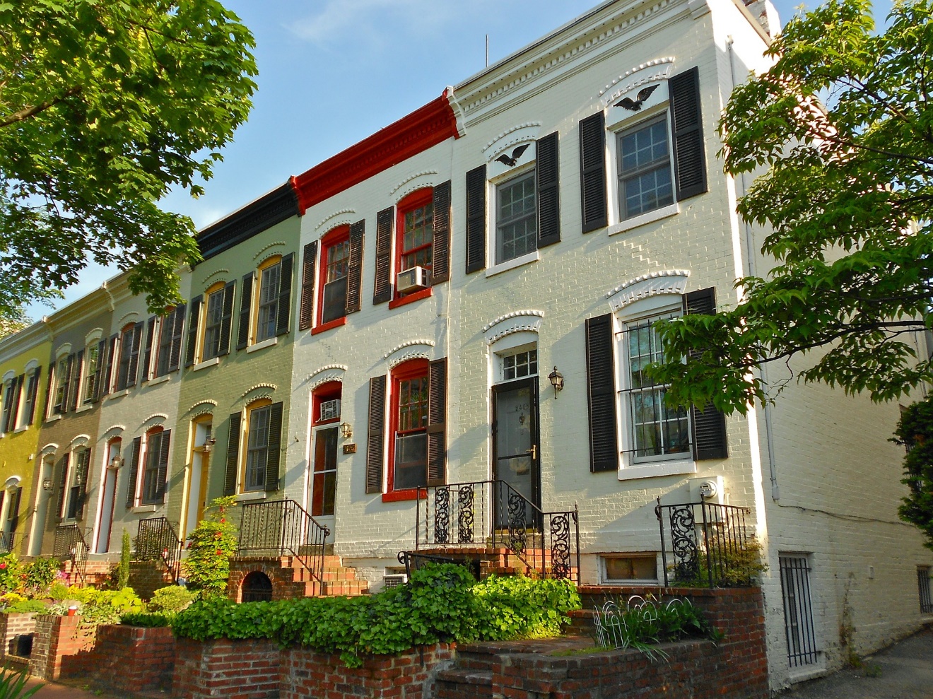 A row of houses with trees with Texas Governor's Mansion in the background Description automatically generated