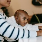 Black mother at her laptop holding a baby