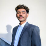 portrait of young businessman on rooftop of office building, looking at camera.