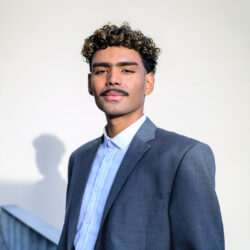 portrait of young businessman on rooftop of office building, looking at camera.