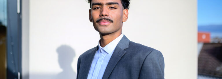 portrait of young businessman on rooftop of office building, looking at camera.