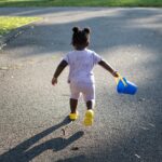 A child carrying a bucket Description automatically generated