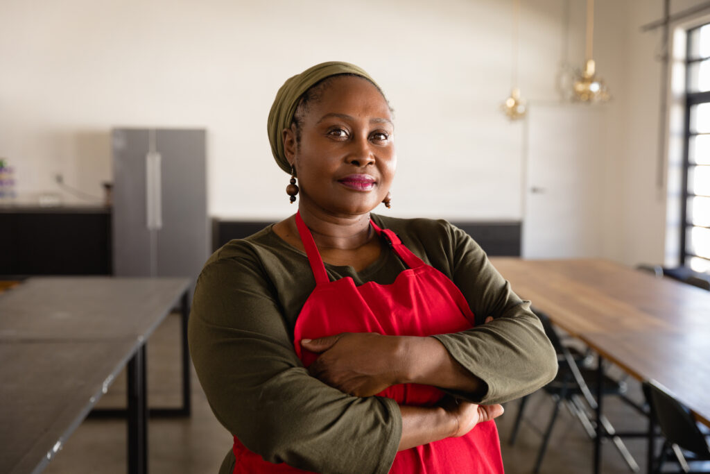 a Black woman in a red apron looks directly at camera